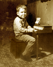 Joseph at age five, seated at toy piano